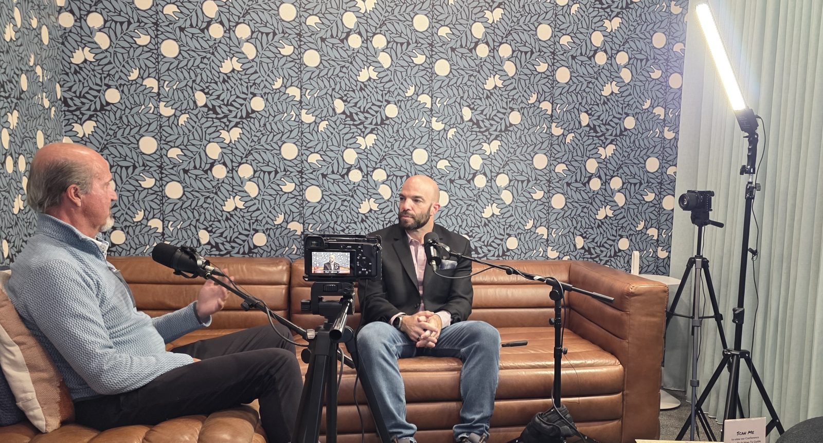 Interview filmed on a leather couch with two microphones and a camera