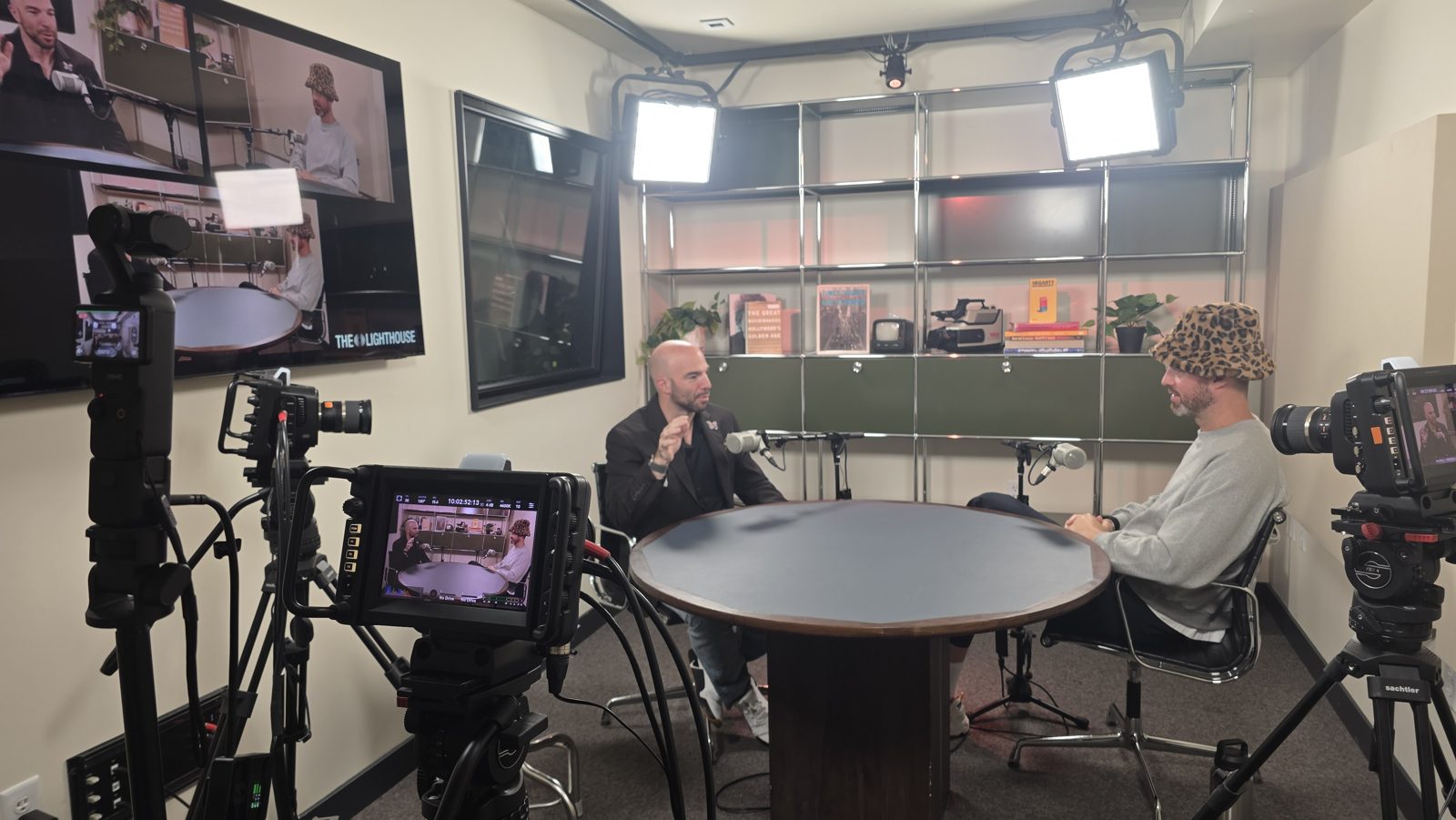 Two hosts recording a video podcast in a studio with three cameras