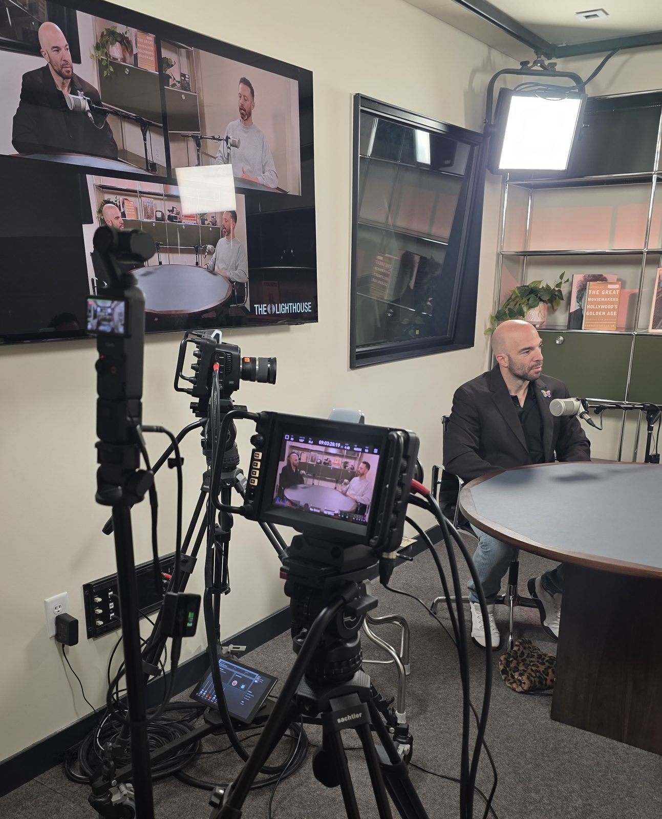 Studio recording with a camera monitor and a wall display showing three camera angles